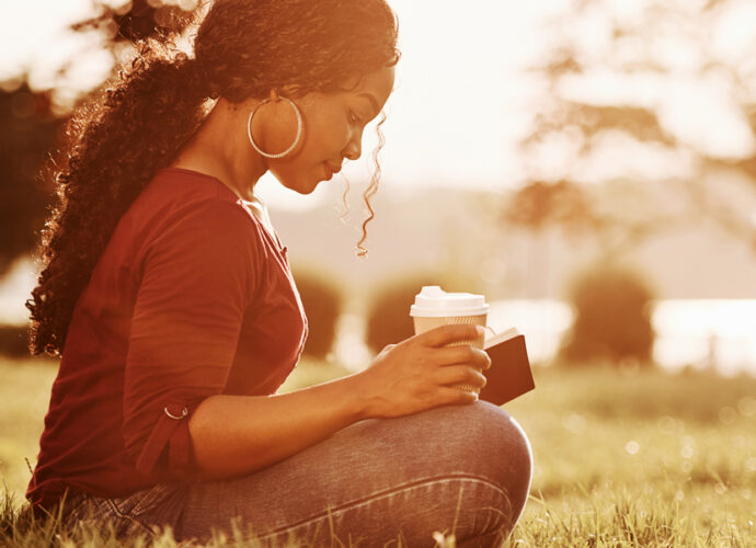 Beautiful woman sitting near a pond reading her Bible
