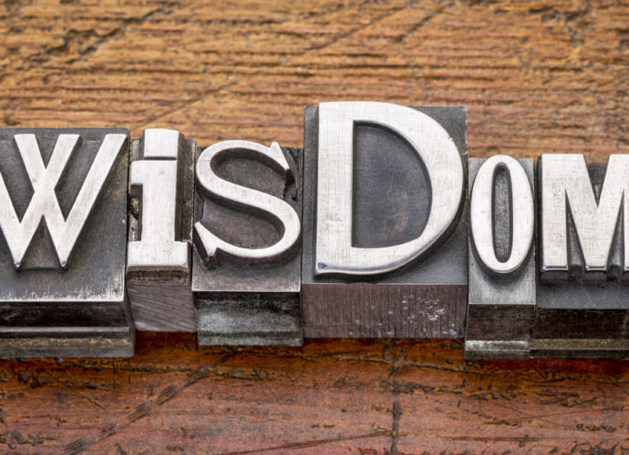 Wood table background with the word Wisdom written across.