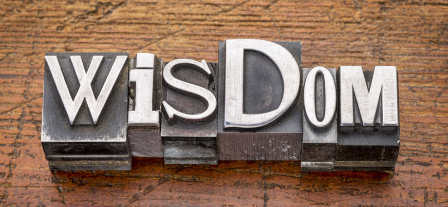 Wood table background with the word Wisdom written across.