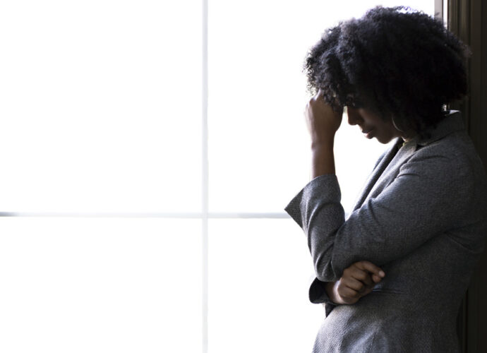 A worried woman standing in front of a window