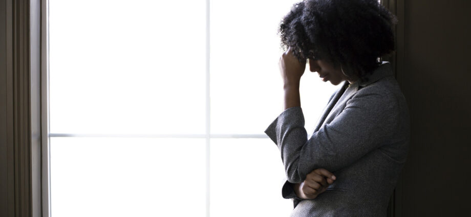 A worried woman standing in front of a window