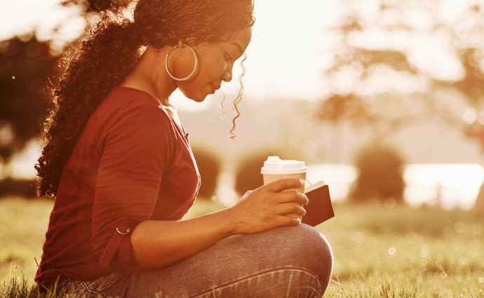 Beautiful woman sitting near a pond reading her Bible