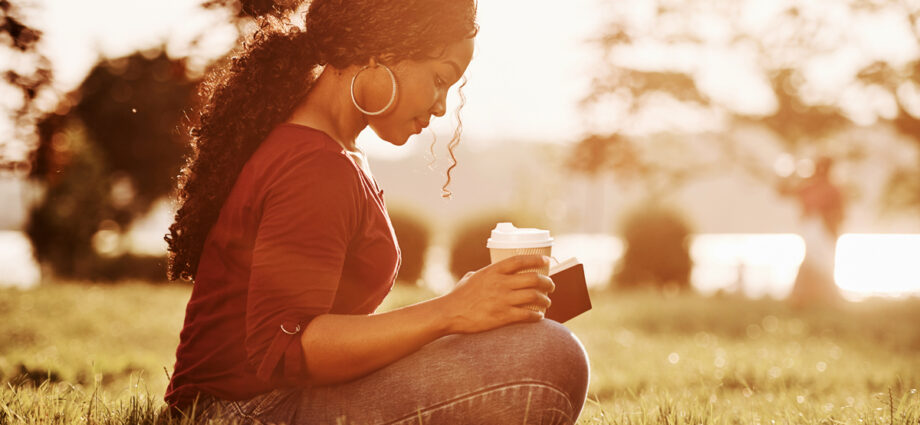 Beautiful woman sitting near a pond reading her Bible